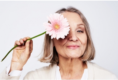 cheerful elegant elderly woman holding flower