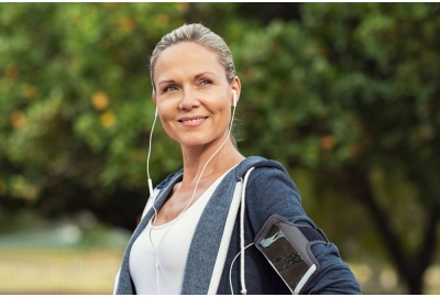 Woman standing outside wearing headphones