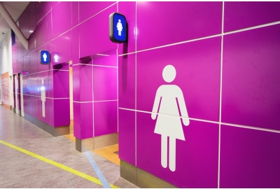 Pink tiled wall with entrances to bathrooms.