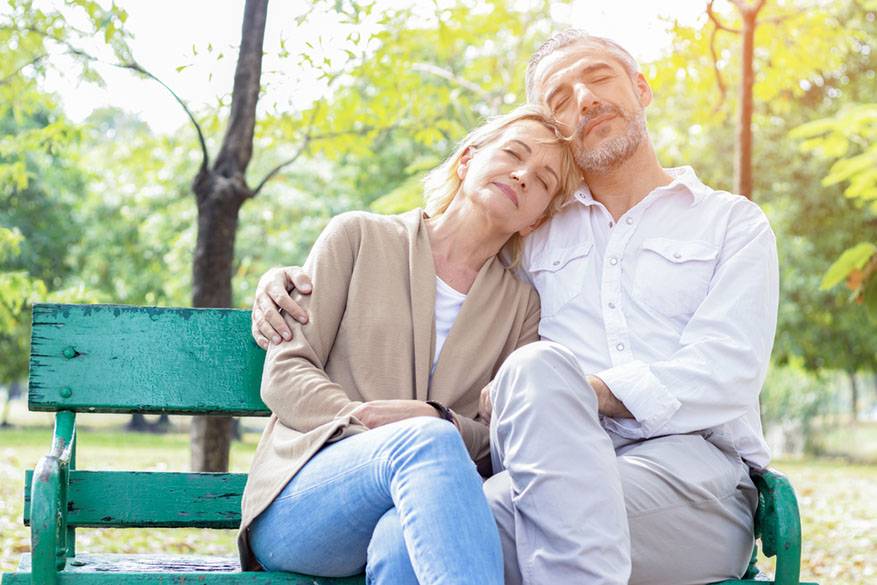 elderly couple embracing on a park bench