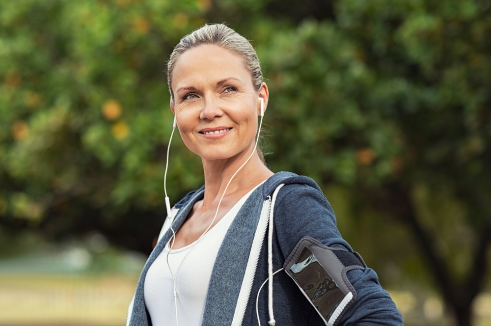 Woman standing outside wearing headphones