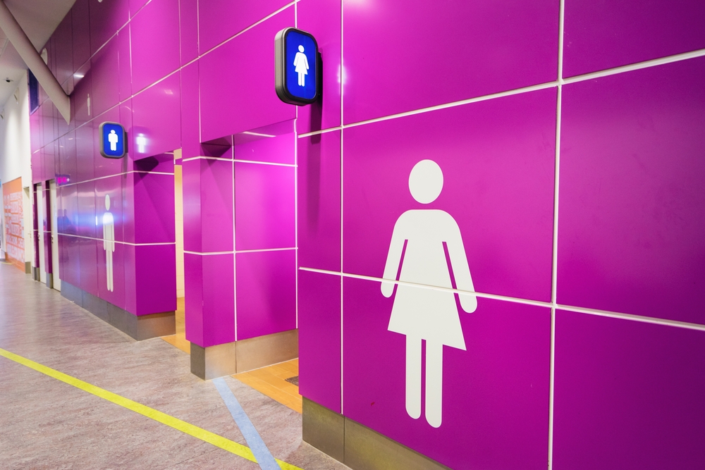 Pink tiled wall with entrances to bathrooms.